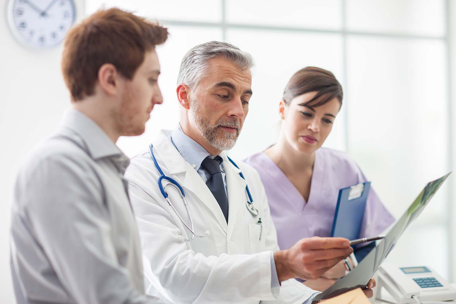 Senior doctor holding results and explaining them to two nurses