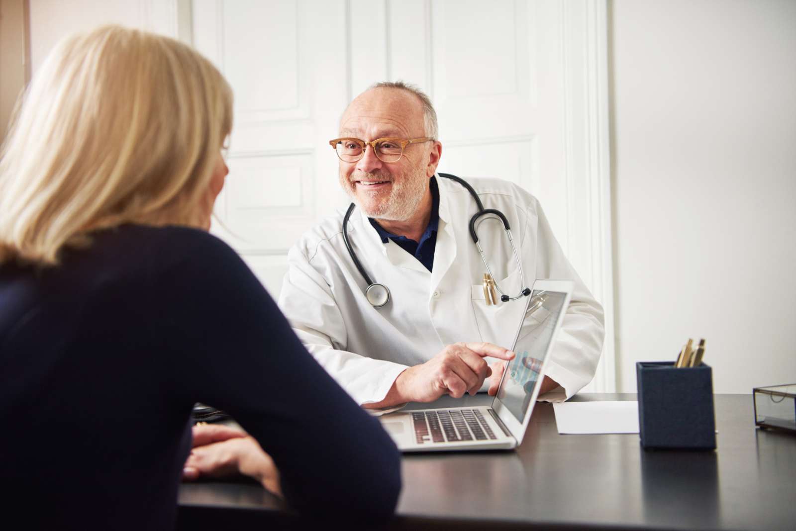 cheerful adult medical worker showing laptop to pa