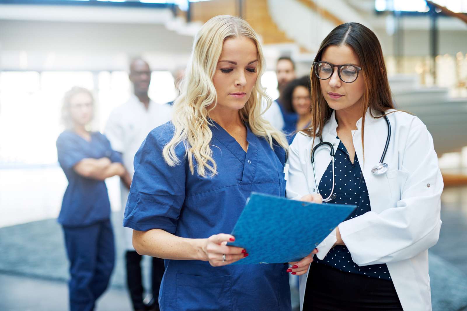 women in hospital standing and browsing papers